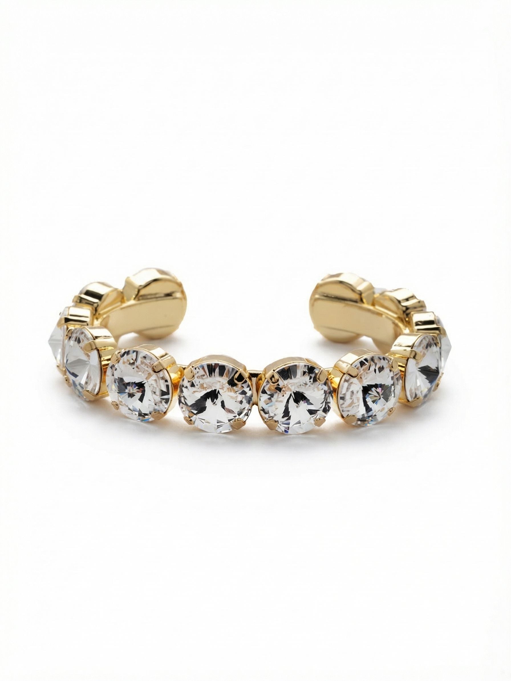 Nadine Cuff Bracelet - 4BEZ17BGCRY - <p>The Nadine Cuff Bracelet offers substantial weight and confident scale. Twelve large round-cut clear crystals are set edge to edge in bright gold-tone bezels creating an unbroken line of light around the arm. The open design slides easily on and off allowing the structure to feel secure yet unrestrictive during a busy day. Worn alone, it commands enough presence to anchor a bare forearm. Stacked alongside your favorite watch, the faceted stones introduce a sharp architectural contrast that catches the light with every movement of your hand.</p><ul>
<li>Oversized round-cut crystals set edge to edge in a bold continuous line</li>
<li>Thick bezel construction that emphasizes the architectural weight of the design</li>
<li>Adjustable open cuff slides on easily</li>
<li>Protective e-coat finish for lasting wear</li>
<li>Includes signature organza pouch for gifting and travel</li>
</ul>