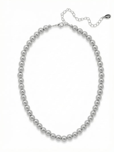 Zola Tennis Necklace - 4NFJ21PDMTL - <p>A continuous line of polished metallic spheres creates a fluid weight that drapes effortlessly along the collarbone. The high-shine palladium finish catches and reflects ambient light, offering a clean, reflective alternative to faceted stones. The rounded beads provide a substantial feel and smooth texture that moves naturally with you. Built with a simple extension chain, the length adjusts to match different necklines, making it a reliable anchor piece for layered chains or a quiet metallic accent on its own.</p><ul>
<li>Continuous line of uniform spherical beads</li>
<li>High-polish metallic finish for a sleek mirror effect</li>
<li>Lobster claw clasp</li>
<li>4-inch adjustable extension chain</li>
<li>Protective e-coat finish for lasting wear</li>
<li>Includes signature organza pouch for gifting and travel</li>
</ul>