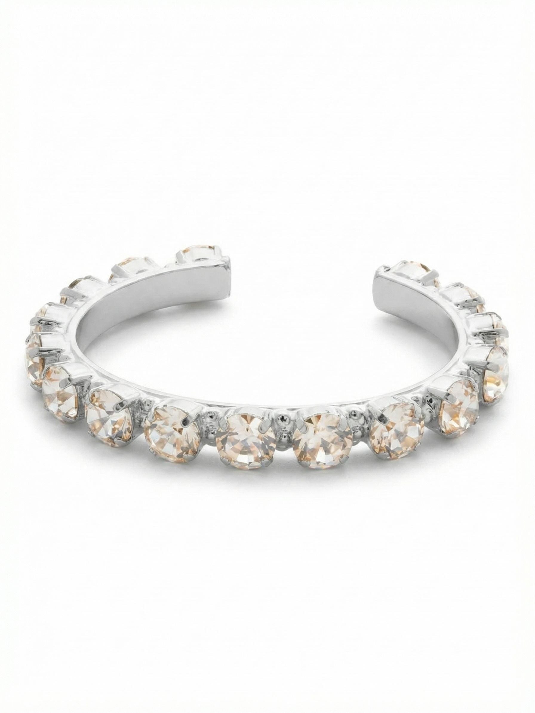 Riveting Romance Cuff Bracelet - BCL23PDCRY - <p>Sixteen substantial round-cut crystals line this open cuff, held securely in a continuous channel setting. The rigid architecture gives the stones a bold, unbroken presence that catches the light from every angle as your hands move. Because it slips straight on, there are no clasps to manage or adjust. The open back allows for a quick, secure fit that anchors nicely below the wristbone. It brings enough weight to ground a stack of thinner chains but carries enough volume to wear quietly on its own.</p><ul>
<li>Continuous channel setting creates an unbroken line of crystals</li>
<li>Large round-cut stones provide substantial scale and volume</li>
<li>Adjustable open cuff slides on easily</li>
<li>Protective e-coat finish for lasting wear</li>
<li>Includes signature organza pouch for gifting and travel</li>
</ul>