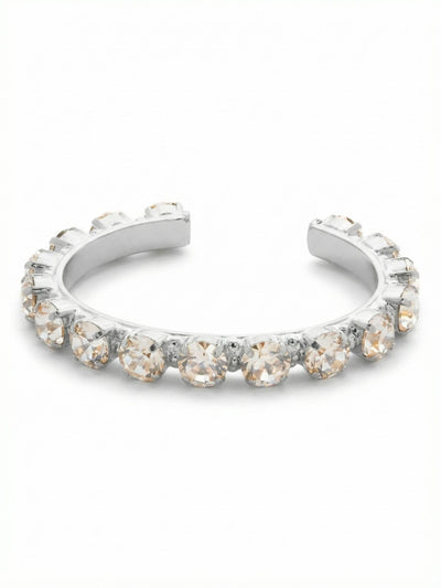 Riveting Romance Cuff Bracelet - BCL23PDCRY - <p>Sixteen substantial round-cut crystals line this open cuff, held securely in a continuous channel setting. The rigid architecture gives the stones a bold, unbroken presence that catches the light from every angle as your hands move. Because it slips straight on, there are no clasps to manage or adjust. The open back allows for a quick, secure fit that anchors nicely below the wristbone. It brings enough weight to ground a stack of thinner chains but carries enough volume to wear quietly on its own.</p><ul>
<li>Continuous channel setting creates an unbroken line of crystals</li>
<li>Large round-cut stones provide substantial scale and volume</li>
<li>Adjustable open cuff slides on easily</li>
<li>Protective e-coat finish for lasting wear</li>
<li>Includes signature organza pouch for gifting and travel</li>
</ul>