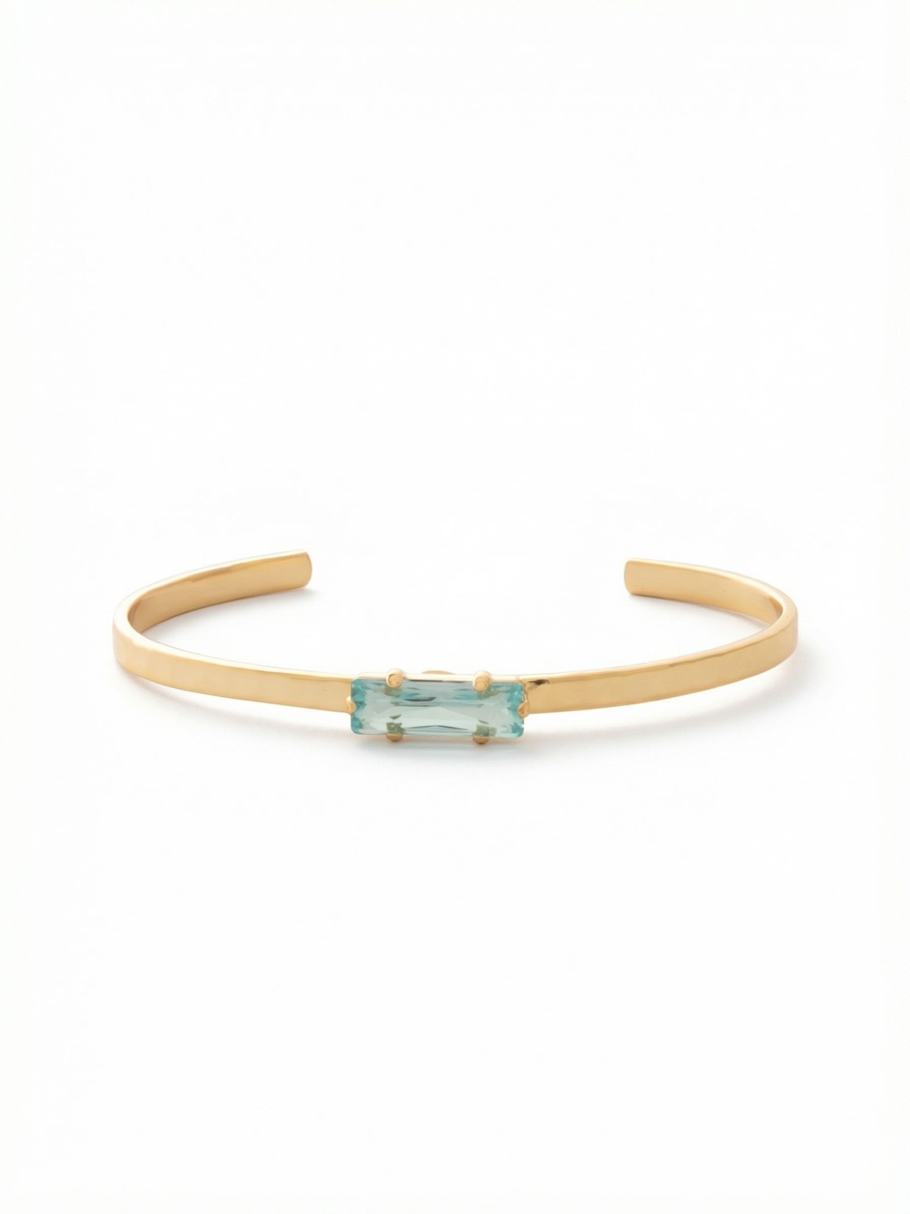Bindi Cuff Bracelet - BCW13BGAQU - <p>A single baguette-cut aquamarine crystal brings a clear wash of color to this streamlined gold-tone cuff. The slender metal band provides a polished foundation, allowing the stepped facets of the solitary stone to catch the light with every movement of your hand. Designed as an open cuff, it slips on effortlessly and adjusts for a secure fit. This piece works quietly on its own as a subtle accent or layers naturally alongside your everyday chains for added dimension.</p><ul>
<li>Horizontally set baguette-cut center crystal</li>
<li>Slender polished metal band designed for easy stacking</li>
<li>Adjustable open cuff slides on easily</li>
<li>Protective e-coat finish for lasting wear</li>
<li>Includes signature organza pouch for gifting and travel</li>
</ul>