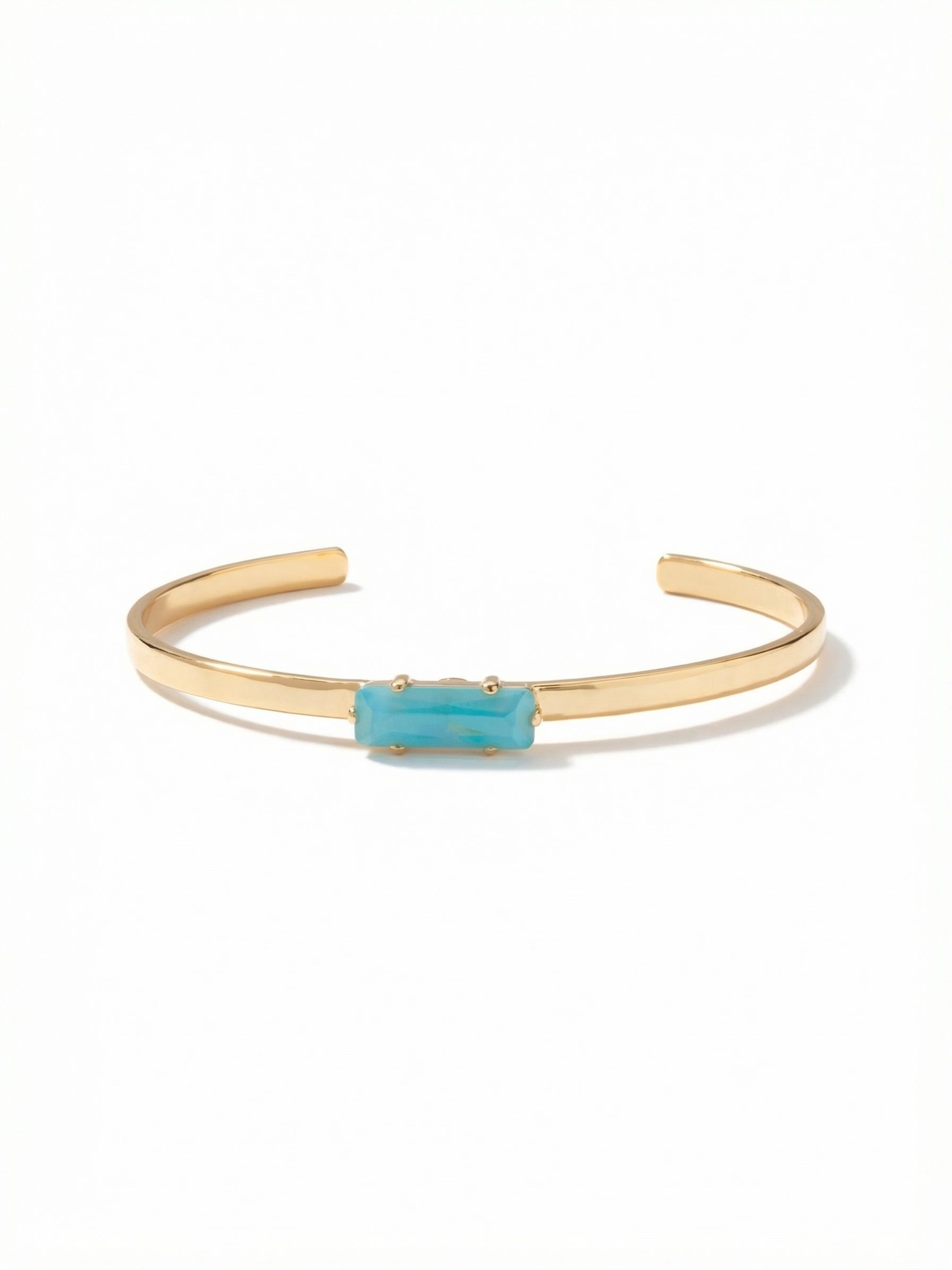 Bindi Cuff Bracelet - BCW13BGSBD - <p>A solitary horizontal baguette anchors this polished metal cuff. The elongated cut of the vibrant teal crystal breaks up the clean, architectural lines, offering a deliberate focal point at the wrist. Designed to slide on easily, the open structure provides a comfortable, lightly adjustable hold that accommodates your daily movement. It holds its own as a quiet standalone piece or functions as a clean base layer when building a textured stack.</p><ul>
<li>Horizontally set baguette crystal creates a clean minimalist focal point</li>
<li>Slender metal band profile built for effortless daily stacking</li>
<li>Adjustable open cuff slides on easily</li>
<li>Protective e-coat finish for lasting wear</li>
<li>Includes signature organza pouch for gifting and travel</li>
</ul>