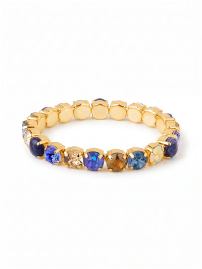 7 inch Sienna Stretch Bracelet - BFD50BGDNM - <p>Deep blue sodalite stones intersperse with faceted sapphire and smoked topaz crystals, forming a rich gradient of color that catches the light as you move. The bright gold settings warm these cool denim hues, framing each round cut with polished structure. Built on a flexible base, the design glides right over your hand, offering immediate comfort and a secure fit without the fuss of a clasp. It maintains its shape while providing the gentle give needed for active, daily wear.</p><ul>
<li>Alternating opaque sodalite and faceted crystals in a repeating round-cut pattern</li>
<li>A balanced palette of deep denim blues and warm earth tones</li>
<li>Stretch easy slip-on design</li>
<li>Protective e-coat finish for lasting wear</li>
<li>Includes signature organza pouch for gifting and travel</li>
</ul>