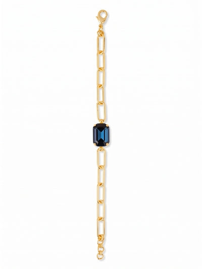 Brynn Paperclip Tennis Bracelet - BFS78BGMON - <p>A substantial emerald-cut crystal in deep Montana blue anchors this modern take on the everyday bracelet. The crisp facets of the central stone provide a sharp contrast to the airy, interlocking bright gold-tone paperclip chain. It brings a calculated geometry to your wrist, moving with a fluidity that feels right beside a favorite watch or layered with slender metal bangles. The open links keep the weight comfortable while maintaining a strong visual presence.</p><ul>
<li>Sharp contrast of an emerald-cut crystal against an airy open-link chain</li>
<li>Substantial central focal point framed by a modern geometric silhouette</li>
<li>Lobster claw clasp</li>
<li>3/4-inch adjustable extension chain</li>
<li>Protective e-coat finish for lasting wear</li>
<li>Includes signature organza pouch for gifting and travel</li>
</ul>