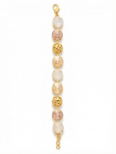 Clementine Tennis Bracelet - BFZ180BGGGO - <p>Warm blush and iridescent crystals alternate with pierced gold-tone metalwork to create a bracelet with substantial visual weight and a surprisingly fluid feel. The larger profile gives this piece clear presence on your arm, while the soft golden palette keeps the look completely versatile for daily wear. Built on an articulated channel setting, the stones catch natural light beautifully in motion. An extension chain allows you to adjust the drape exactly to your preference.</p><ul>
<li>Alternating sequence of oversized round crystals and textured filigree spheres</li>
<li>Warm tonal palette mixing blush pinks with shifting aurora borealis light</li>
<li>Lobster claw clasp</li>
<li>3/4-inch adjustable extension chain</li>
<li>Protective e-coat finish for lasting wear</li>
<li>Includes signature organza pouch for gifting and travel</li>
</ul>