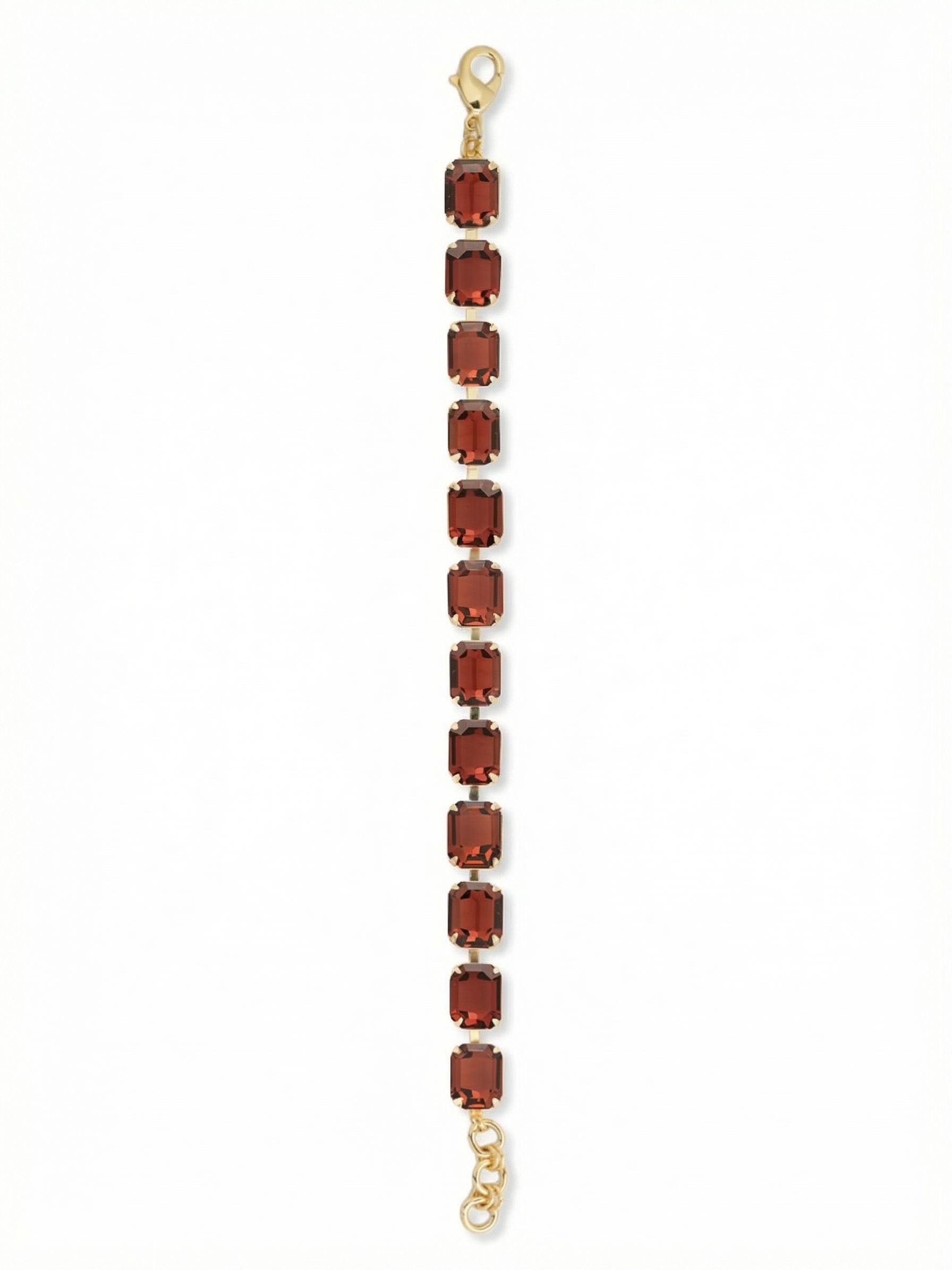 Octavia Repeating Tennis Bracelet - BFZ6BGBUR - <p>Deep burgundy emerald-cut crystals establish a steady, geometric rhythm. The stepped facets of these rectangular stones capture the light with quiet authority, creating a rich, structural gleam rather than a scattered sparkle. Warmed by the bright gold-tone setting, the continuous line brings substantial color to everyday styling. The flexible linked construction allows the piece to move naturally with you throughout the day. An adjustable extension chain lets you fine-tune the drape for your preferred fit.</p><ul>
<li>Continuous line of emerald-cut crystals for a bold, geometric profile</li>
<li>Stepped rectangular facets create a structural gleam</li>
<li>Lobster claw clasp</li>
<li>3/4-inch adjustable extension chain</li>
<li>Protective e-coat finish for lasting wear</li>
<li>Includes signature organza pouch for gifting and travel</li>
</ul>