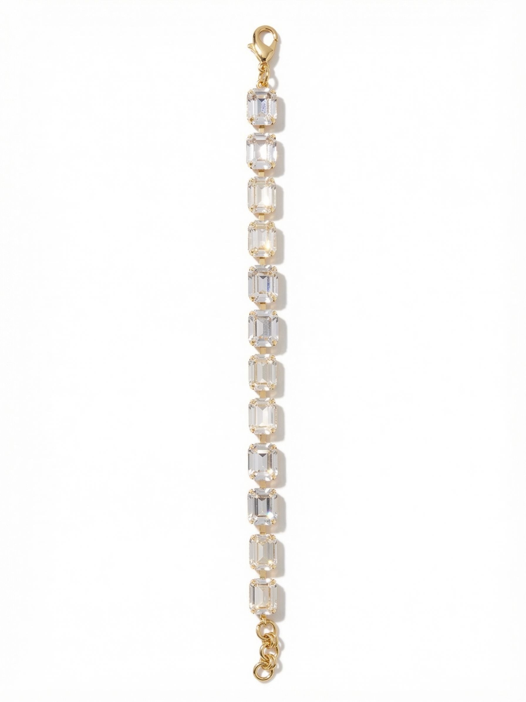 Octavia Repeating Tennis Bracelet - BFZ6BGCRY - <p>Twelve substantial emerald-cut clear crystals form an unbroken line of quiet brilliance. Because they are step-cut, these stones catch the light in long, clean flashes that feel distinct and deliberate. The flexible channel chain construction allows the bracelet to conform easily as you move. It carries enough visual weight to wear beautifully on its own, yet the classic linear profile layers cleanly with your daily watch. An integrated extension chain ensures a comfortable, customized drape.</p><ul>
<li>Emerald-cut clear crystals deliver continuous, linear flashes of light</li>
<li>Articulated channel chain construction allows for flexible daily movement</li>
<li>Lobster claw clasp</li>
<li>3/4-inch adjustable extension chain</li>
<li>Protective e-coat finish for lasting wear</li>
<li>Includes signature organza pouch for gifting and travel</li>
</ul>