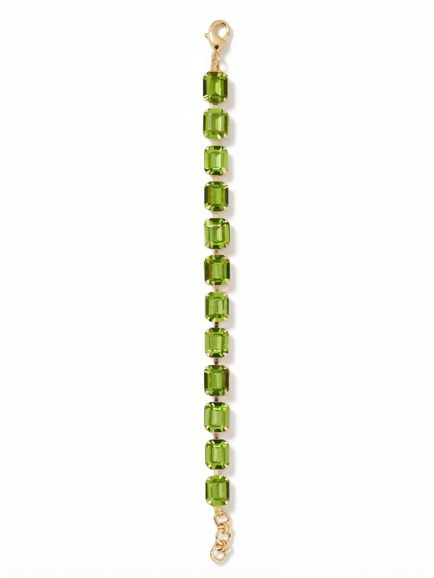 Octavia Repeating Tennis Bracelet - BFZ6BGPER - <p>A continuous line of emerald-cut peridot crystals brings clean, architectural geometry to the wrist. The stones' step facets catch the light with every movement, creating a steady rhythm of vibrant color. Built on a flexible kette chain, the bracelet moves fluidly with your gestures, offering a substantial presence without feeling heavy. It layers effortlessly with classic metal bangles or anchors your daily jewelry rotation on its own. An adjustable extension chain ensures a tailored fit.</p><ul>
<li>Continuous row of emerald-cut crystals creating a bold linear statement</li>
<li>Flexible channel chain construction that moves naturally with the wrist</li>
<li>Lobster claw clasp</li>
<li>3/4-inch adjustable extension chain</li>
<li>Protective e-coat finish for lasting wear</li>
<li>Includes signature organza pouch for gifting and travel</li>
</ul>
