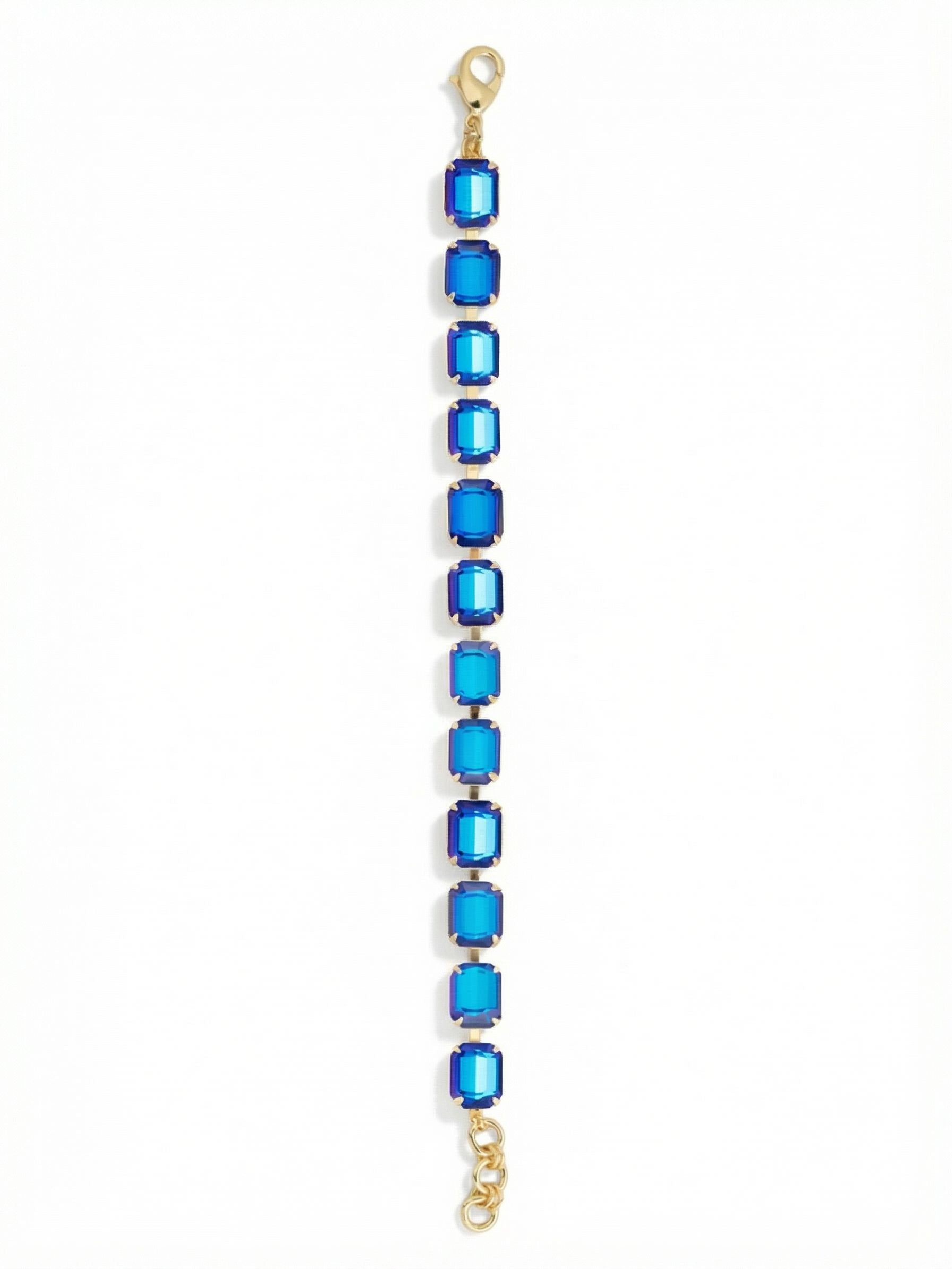 Octavia Repeating Tennis Bracelet - BFZ6BGRBD - <p>Twelve emerald-cut crystals line up in a continuous rhythm of deep blue. The flexible channel chain allows each substantial stone to catch the light as you move, turning a familiar silhouette into a deliberate statement. An extension chain lets you find your exact fit so the weight stays comfortably balanced. Wear this piece alone to anchor a tailored sleeve, or slide it on next to your daily watch for an immediate shift in mood.</p><ul>
<li>Continuous line of emerald-cut crystals</li>
<li>Flexible channel chain allows fluid movement</li>
<li>Lobster claw clasp</li>
<li>3/4-inch adjustable extension chain</li>
<li>Protective e-coat finish for lasting wear</li>
<li>Includes signature organza pouch for gifting and travel</li>
</ul>