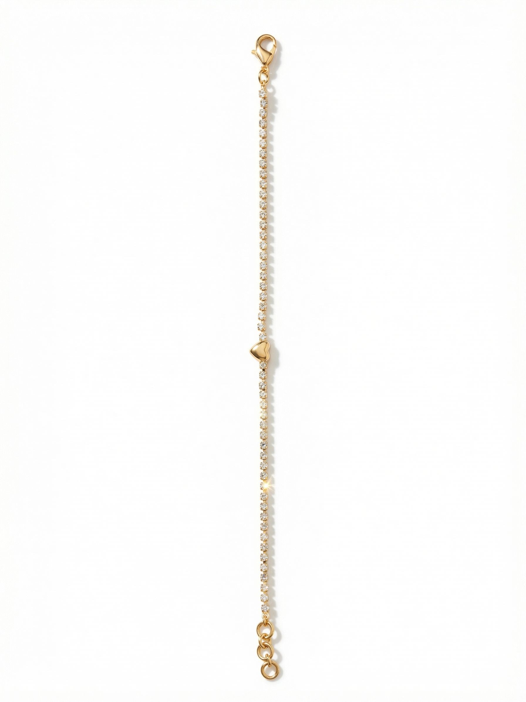Mini Marnie Heart Tennis Bracelet - BGF5BGCRY - <p>A delicate line of faceted crystals wraps the wrist in a continuous thread of light, interrupted only by a single polished heart. The fine rhinestone chain moves naturally with you as you go about your day, offering a quiet, constant glimmer. Whether worn alone as a subtle touch of warmth or layered seamlessly into an established stack of bangles, the included extension chain ensures a comfortable, customized drape.</p><ul>
<li>Polished heart motif integrated into a continuous line of crystals</li>
<li>Ultra-slim profile designed for effortless daily layering</li>
<li>Lobster claw clasp</li>
<li>3/4-inch adjustable extension chain</li>
<li>Protective e-coat finish for lasting wear</li>
<li>Includes signature organza pouch for gifting and travel</li>
</ul>
