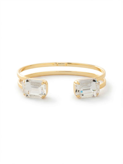 Brynn Adjustable Cuff Bracelet - BGI2BGCRY - <p>The Brynn Cuff balances architectural structure with serious light play. Two parallel bands of bright gold-tone metal wrap over the wrist, anchoring a pair of oversized emerald-cut clear crystals at the opening. The step cuts of the stones catch light in broad, linear flashes as you move. Because the cuff is open, it slides on easily and flexes gently to conform to your shape, making it a comfortable standalone piece or a strong geometric anchor for your everyday stack.</p><ul>
<li>Double-wire design creates lightweight visual structure</li>
<li>Emerald-cut stones cast distinct linear light reflections</li>
<li>Adjustable front open cuff slides on easily</li>
<li>Protective e-coat finish for lasting wear</li>
<li>Includes signature organza pouch for gifting and travel</li>
</ul>