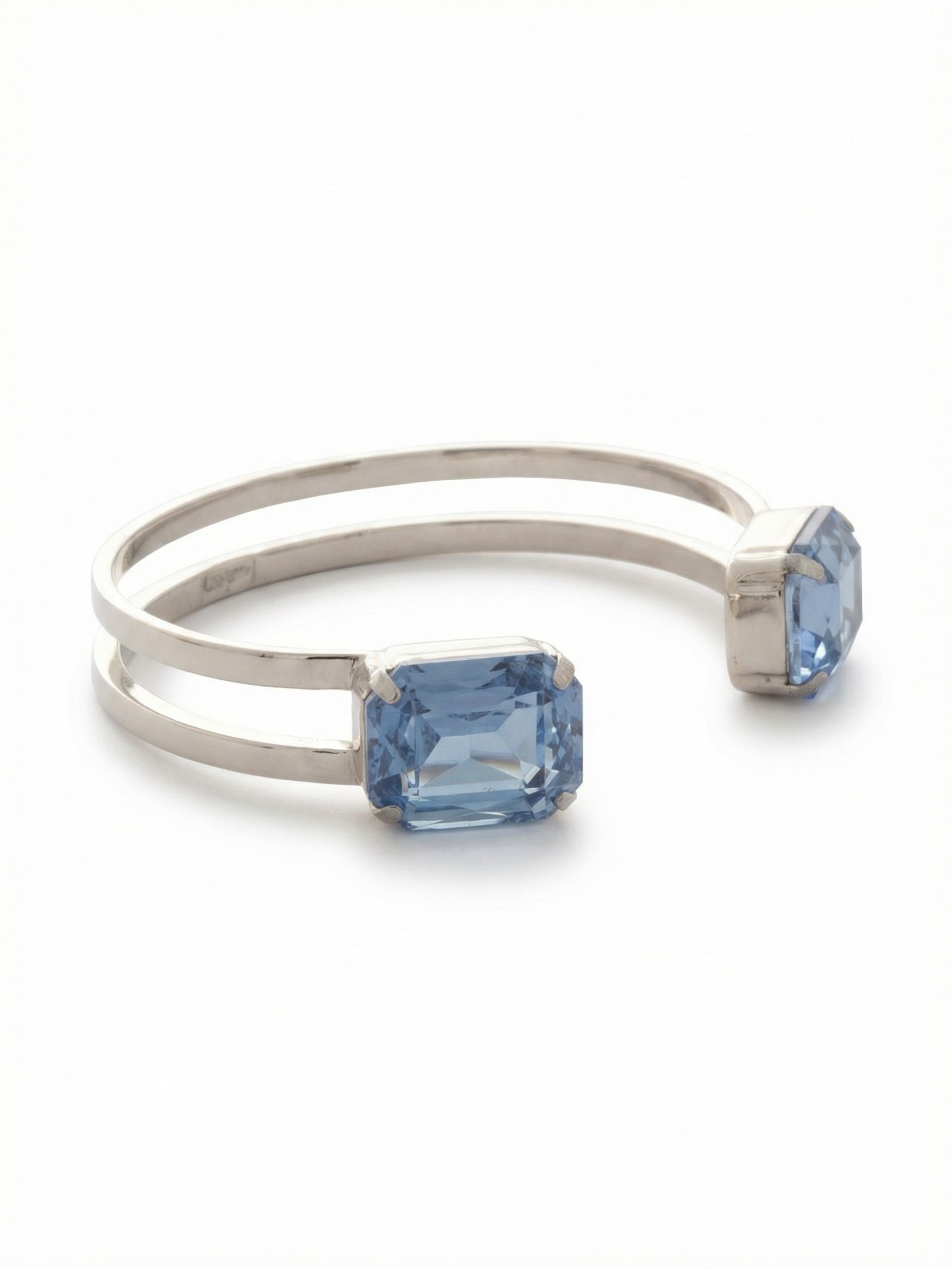 Brynn Adjustable Cuff Bracelet - BGI2PDLTS - <p>Clean architectural lines meet noticeable crystal weight in this double-banded cuff. Two parallel metallic arcs create a lightweight frame that slips easily over the hand, ending in twin emerald-cut pale blue sapphires. The open slide-on construction offers a flexible fit that adapts to your daily movement without feeling restrictive. The structural negative space brings visual interest when worn solo, while the squared crystal ends provide a bold anchor for a stacked wrist.</p><ul>
<li>Twin large-scale emerald cuts create bold endpoints at the cuff opening</li>
<li>Double parallel bands frame the wrist with structural negative space</li>
<li>Adjustable open cuff slides on easily</li>
<li>Protective e-coat finish for lasting wear</li>
<li>Includes signature organza pouch for gifting and travel</li>
</ul>