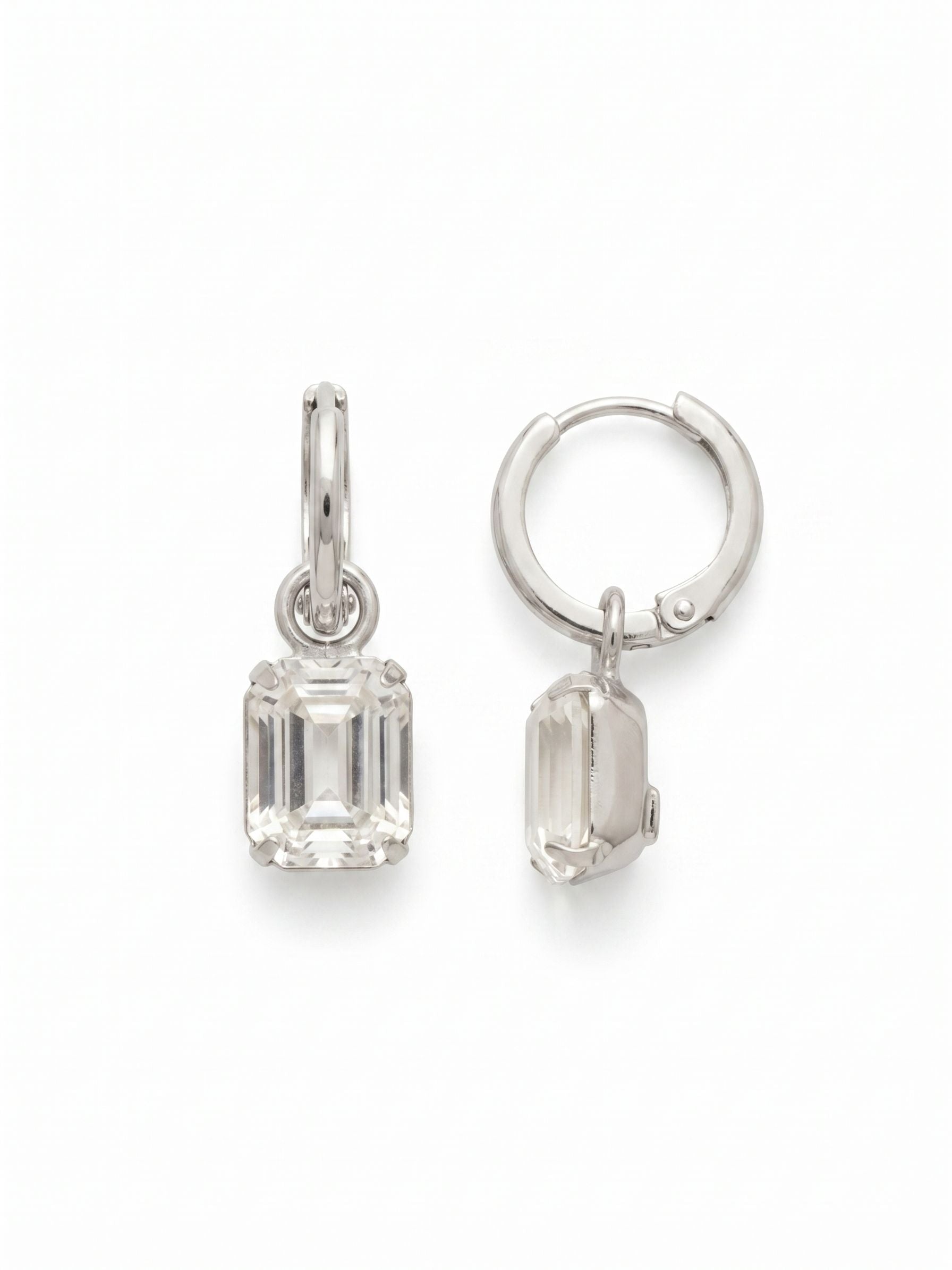 Octavia Huggie Hoop Earrings - EFS34PDCRY - <p>A refined approach to the everyday drop earring. Suspended from a sleek hoop, a crisp emerald-cut clear crystal creates subtle movement, catching the light in clean, linear flashes. The secure huggie closure offers a comfortable, close fit keeping these lightweight earrings anchored easily through long days. At exactly an inch in length, they provide a focused geometry that quietly brightens the face while remaining completely effortless to wear.</p><ul>
<li>Crisp emerald-cut crystals deliver clean, geometric flashes of light</li>
<li>Articulated drop setting allows the stone to move freely with you</li>
<li>Huggie hoop with click-shut closure</li>
<li>Protective e-coat finish for lasting wear</li>
<li>Includes signature organza pouch for gifting and travel</li>
</ul>