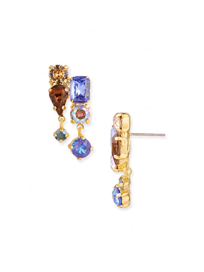 Moxie Dangle Earrings - EGI7BGDNM - <p>Deep sapphire blues and warm smoke topaz tones gather in an intricate cluster of mixed cuts, anchored closely to the ear. Below this solid structure, two solitary crystals swing freely to catch the light with every turn of the head. The bright gold-tone setting adds a rich contrast to the varied shapes. A pressure-fit comfort back holds the entire piece securely in place, keeping the heavier top section perfectly upright and balanced from morning to evening.</p><ul>
<li>Cluster of emerald, pear, and round cuts in a structured setting</li>
<li>Two lower crystals swing independently with natural movement</li>
<li>Post with oversized comfort-clutch back</li>
<li>Protective e-coat finish for lasting wear</li>
<li>Includes signature organza pouch for gifting and travel</li>
</ul>