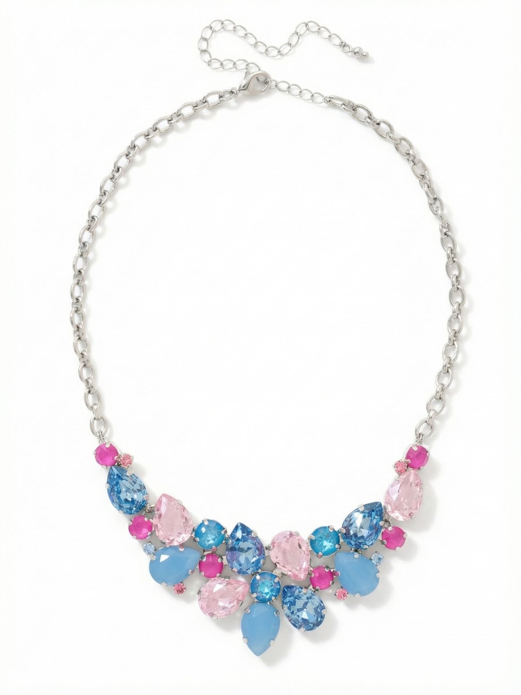 Dare To Pear Crystal Statement Necklace - NCP3PDPBZ - <p>This crystal statement necklace creates a bold focal point at the collarbone. A dense cluster of pear and round cut crystals mixes translucent light rose with opaque air blue opal and deep sapphire tones. This contrast in stone finishes adds a subtle depth to the arrangement. Suspended from a sturdy rolo chain, the substantial weight of the bib drapes securely whether worn high near the collar or lowered to fill an open neckline. The extension chain allows for precise placement to suit your preferred silhouette.</p><ul>
<li>Mix of pear and round cuts arranged in a dense cascading cluster</li>
<li>Contrast between translucent crystal elements and opaque opal finishes</li>
<li>Lobster claw clasp</li>
<li>4-inch adjustable extension chain</li>
<li>Protective e-coat finish for lasting wear</li>
<li>Includes signature organza pouch for gifting and travel</li>
</ul>
