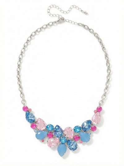 Dare To Pear Crystal Statement Necklace - NCP3PDPBZ - <p>This crystal statement necklace creates a bold focal point at the collarbone. A dense cluster of pear and round cut crystals mixes translucent light rose with opaque air blue opal and deep sapphire tones. This contrast in stone finishes adds a subtle depth to the arrangement. Suspended from a sturdy rolo chain, the substantial weight of the bib drapes securely whether worn high near the collar or lowered to fill an open neckline. The extension chain allows for precise placement to suit your preferred silhouette.</p><ul>
<li>Mix of pear and round cuts arranged in a dense cascading cluster</li>
<li>Contrast between translucent crystal elements and opaque opal finishes</li>
<li>Lobster claw clasp</li>
<li>4-inch adjustable extension chain</li>
<li>Protective e-coat finish for lasting wear</li>
<li>Includes signature organza pouch for gifting and travel</li>
</ul>