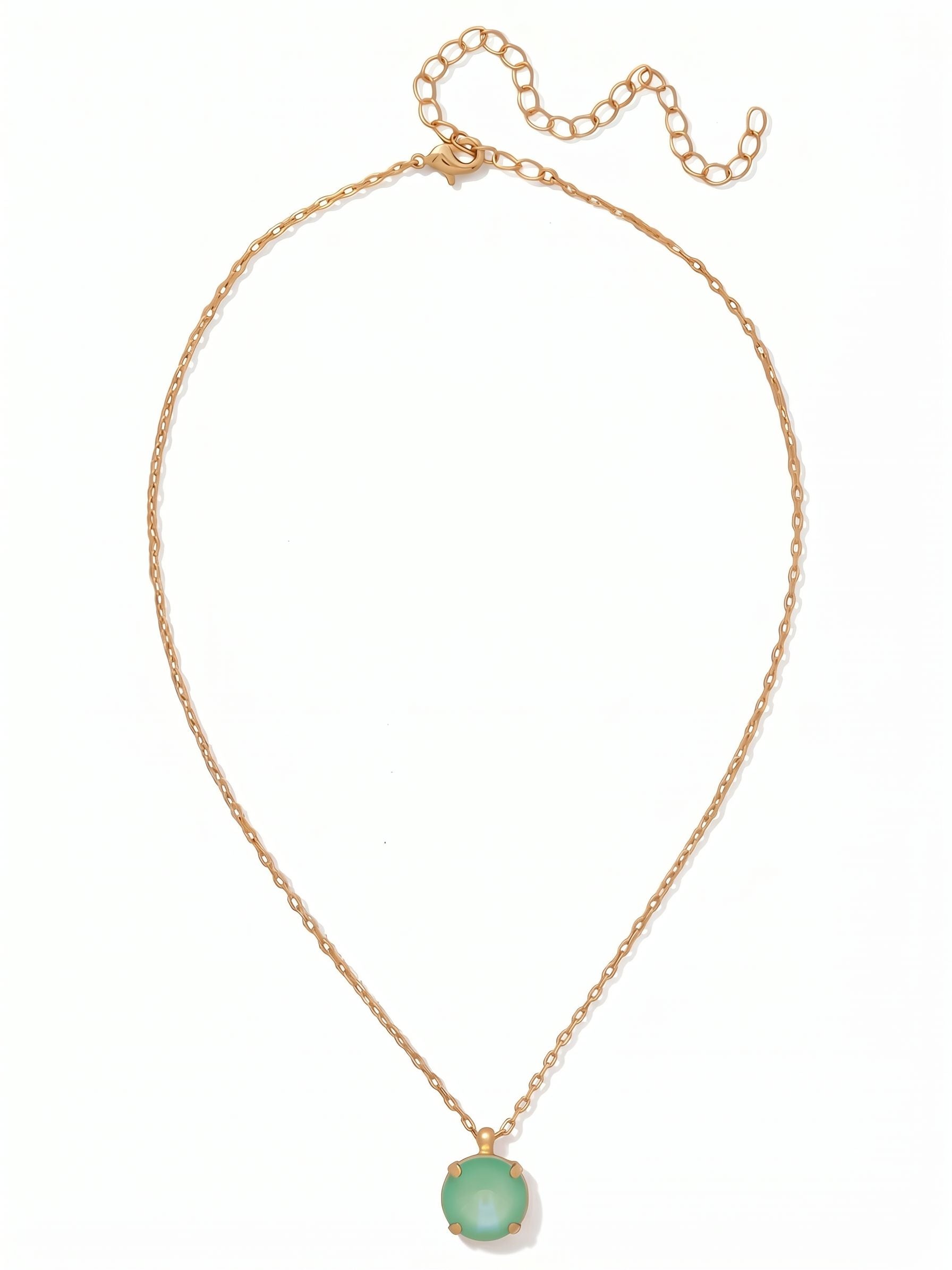 Nadine Pendant Necklace - NDB83BGMND - <p>A single, substantial round crystal in a soft mint hue anchors this fine cable chain. At sixteen inches, the pendant finds its natural resting place right at the collarbone, bringing a quiet focal point of color to an open neckline or a crisp white shirt. The bright gold-tone setting adds subtle warmth to the cool green stone. With the built-in extension chain, the piece easily adjusts to layer beneath longer chains or holds its own as an everyday signature.</p><ul>
<li>Single oversized round crystal creates a distinct focal point</li>
<li>Fine cable chain visually balances the weight of the central stone</li>
<li>Lobster claw clasp</li>
<li>4-inch adjustable extension chain</li>
<li>Protective e-coat finish for lasting wear</li>
<li>Includes signature organza pouch for gifting and travel</li>
</ul>