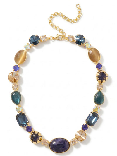 Tatiana Tennis Necklace - NEP58BGDNM - <p>A substantial take on the classic tennis line. The Tatiana anchors at the collarbone with a generous oval of opaque sodalite, giving way to a varied rhythm of emerald-cut crystals, pear-shaped labradorite, and smooth toffee cat's eye. This piece balances deep, moody blues with the unexpected warmth of golden shadow crystals. The flexible kette chain allows the heavier stone weights to drape naturally across the neckline. An included extension chain lets you fine-tune the drop to frame an open collar or sit comfortably over a high knit.</p><ul>
<li>Alternating opaque sodalite and translucent crystals that create deep visual contrast</li>
<li>Mixed stone scale and varied shapes for a substantial collarbone presence</li>
<li>Lobster claw clasp</li>
<li>4-inch adjustable extension chain</li>
<li>Protective e-coat finish for lasting wear</li>
<li>Includes signature organza pouch for gifting and travel</li>
</ul>
