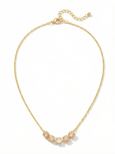 Shaughna Tennis Necklace - NFC84BGGGO - <p>A fine cable chain anchors five faceted crystals at the collarbone, creating a quiet point of light that shifts with your movement. A warm gradient of silk and golden shadow tones flanks a bright center stone, catching ambient light effortlessly. Built with a slender profile that feels entirely weightless on the skin, the piece adjusts smoothly to rest exactly where you want it. It layers cleanly with heavier chains or holds its own beautifully as a daily signature.</p><ul>
<li>Five clustered round crystals create a distinct focal point on a delicate cable chain</li>
<li>Warm silk and golden shadow stones frame a bright white center crystal</li>
<li>Lobster claw clasp</li>
<li>4-inch adjustable extension chain</li>
<li>Protective e-coat finish for lasting wear</li>
<li>Includes signature organza pouch for gifting and travel</li>
</ul>