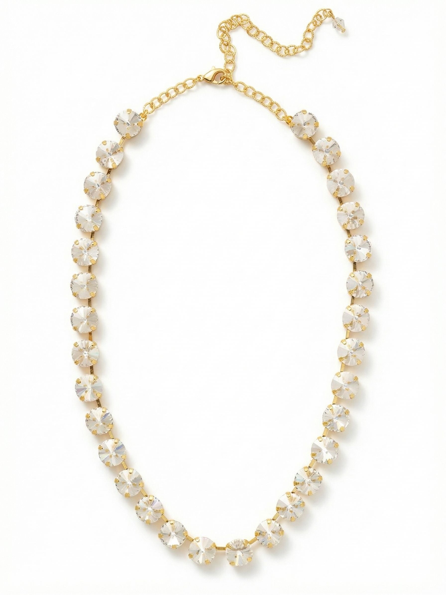 Mara Tennis Necklace - NFD75BGCRY - <p>A continuous line of oversized round crystals brings immediate light to the face. The substantial half-inch width gives this tennis necklace a grounded presence, while the articulated chain construction allows each stone to move slightly, catching light from every angle. It drapes naturally around the collarbone with a comfortable weight that reminds you of the handcrafted quality. An attached four-inch extension chain lets you adjust the length, making it easy to wear closely as a choker or dropped slightly lower over a structured neckline.</p><ul>
<li>Oversized round crystals create a substantial continuous line of light</li>
<li>Articulated chain construction allows the stones to drape gracefully at the collarbone</li>
<li>Lobster claw clasp</li>
<li>Protective e-coat finish for lasting wear</li>
<li>Includes signature organza pouch for gifting and travel</li>
</ul>