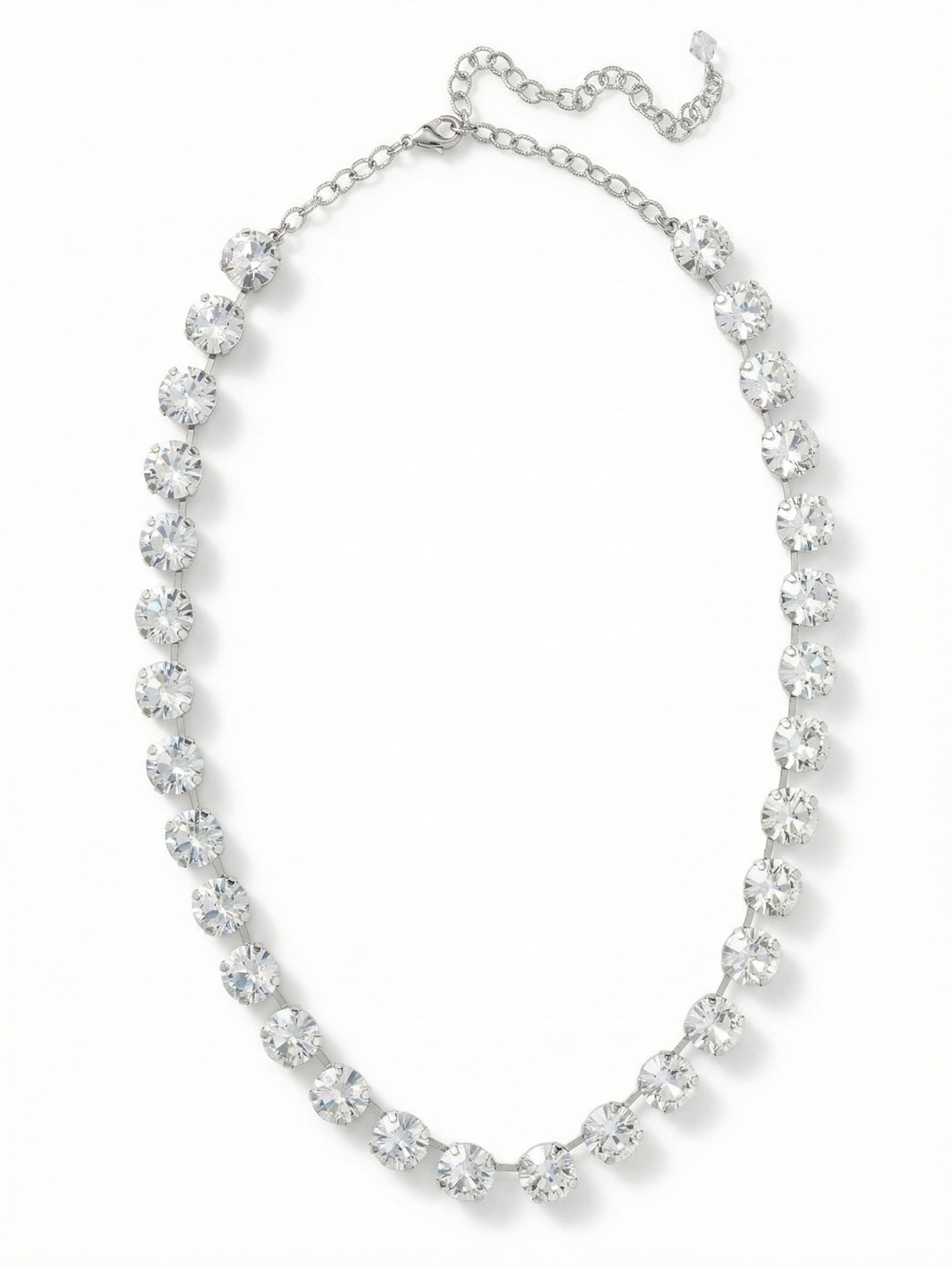 Mara Tennis Necklace - NFD75PDCRY - <p>Thirty significant round-cut clear crystals create an unbroken line of light at the collarbone. The Mara necklace carries a satisfying weight, anchored by a fluid channel chain that articulates beautifully with every turn of the head. At half an inch wide, these stones offer a substantial presence that grounds a simple cotton t-shirt just as easily as an evening silhouette. The integrated extension chain allows you to precisely adjust the drop, finding the exact placement to complement whatever neckline you choose to wear.</p><ul>
<li>Thirty substantial round crystals set in an articulating channel chain</li>
<li>Unbroken half-inch width provides significant presence at the collarbone</li>
<li>Lobster claw clasp</li>
<li>Protective e-coat finish for lasting wear</li>
<li>Includes signature organza pouch for gifting and travel</li>
</ul>