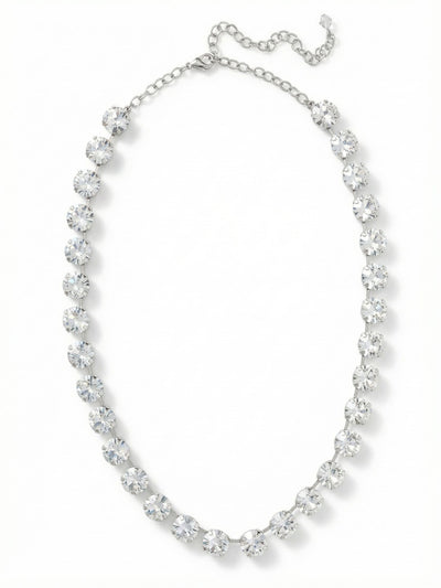 Mara Tennis Necklace - NFD75PDCRY - <p>Thirty significant round-cut clear crystals create an unbroken line of light at the collarbone. The Mara necklace carries a satisfying weight, anchored by a fluid channel chain that articulates beautifully with every turn of the head. At half an inch wide, these stones offer a substantial presence that grounds a simple cotton t-shirt just as easily as an evening silhouette. The integrated extension chain allows you to precisely adjust the drop, finding the exact placement to complement whatever neckline you choose to wear.</p><ul>
<li>Thirty substantial round crystals set in an articulating channel chain</li>
<li>Unbroken half-inch width provides significant presence at the collarbone</li>
<li>Lobster claw clasp</li>
<li>Protective e-coat finish for lasting wear</li>
<li>Includes signature organza pouch for gifting and travel</li>
</ul>