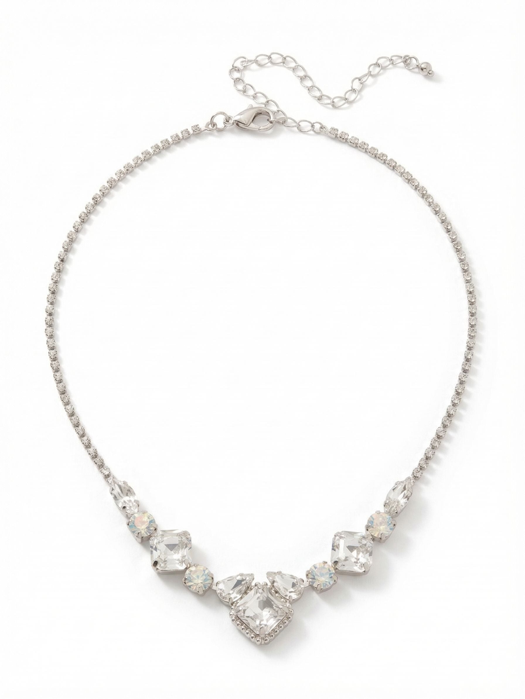 Izzy Crystal Chain Tennis Necklace - NFY400PDCLA - <p>A delicate line of rhinestone chain descends into a concentrated arrangement of light and texture. Sharp square crystals anchor the center, balanced by the softer presence of milky white opals and clear pear cuts. This combination of geometric shapes and contrasting clarities draws the eye directly to the collarbone. Built with a generous extension chain, the necklace adjusts to complement a crisp buttoned shirt or a draped neckline, bringing a quiet focus to your daily rotation.</p><ul>
<li>Contrast of sharp geometric crystal cuts against soft white opals</li>
<li>Delicate rhinestone chain culminating in a complex central motif</li>
<li>Lobster claw clasp</li>
<li>4-inch adjustable extension chain</li>
<li>Protective e-coat finish for lasting wear</li>
<li>Includes signature organza pouch for gifting and travel</li>
</ul>