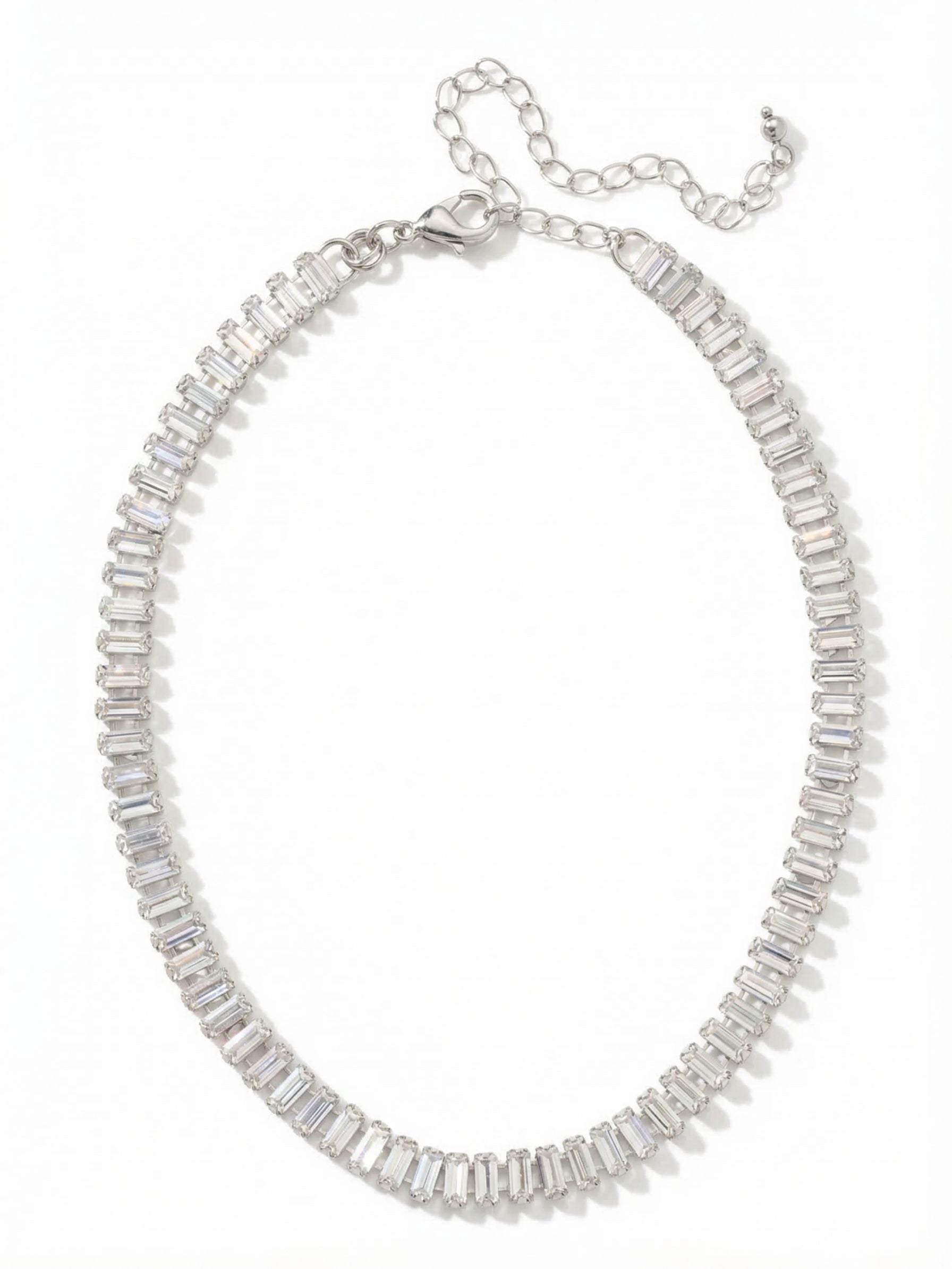 Bianca Choker Tennis Necklace - NFY55PDCRY - <p>The Bianca Choker places a continuous sequence of clear baguette crystals directly at the base of the neck. Set closely together in an articulated channel chain, the stones flex naturally to map the curve of your collarbone. Baguette crystals offer a step-cut facet, creating a clean, mirrored flash rather than a scattered sparkle. With an included extension chain, you can wear this piece high as a structured collar or let it drop slightly to anchor a layered look.</p><ul>
<li>Articulated channel chain allows the sequence of stones to flex naturally</li>
<li>Step-cut baguette faceting provides a sleek, mirrored reflection</li>
<li>Lobster claw clasp</li>
<li>4-inch adjustable extension chain</li>
<li>Protective e-coat finish for lasting wear</li>
<li>Includes signature organza pouch for gifting and travel</li>
</ul>