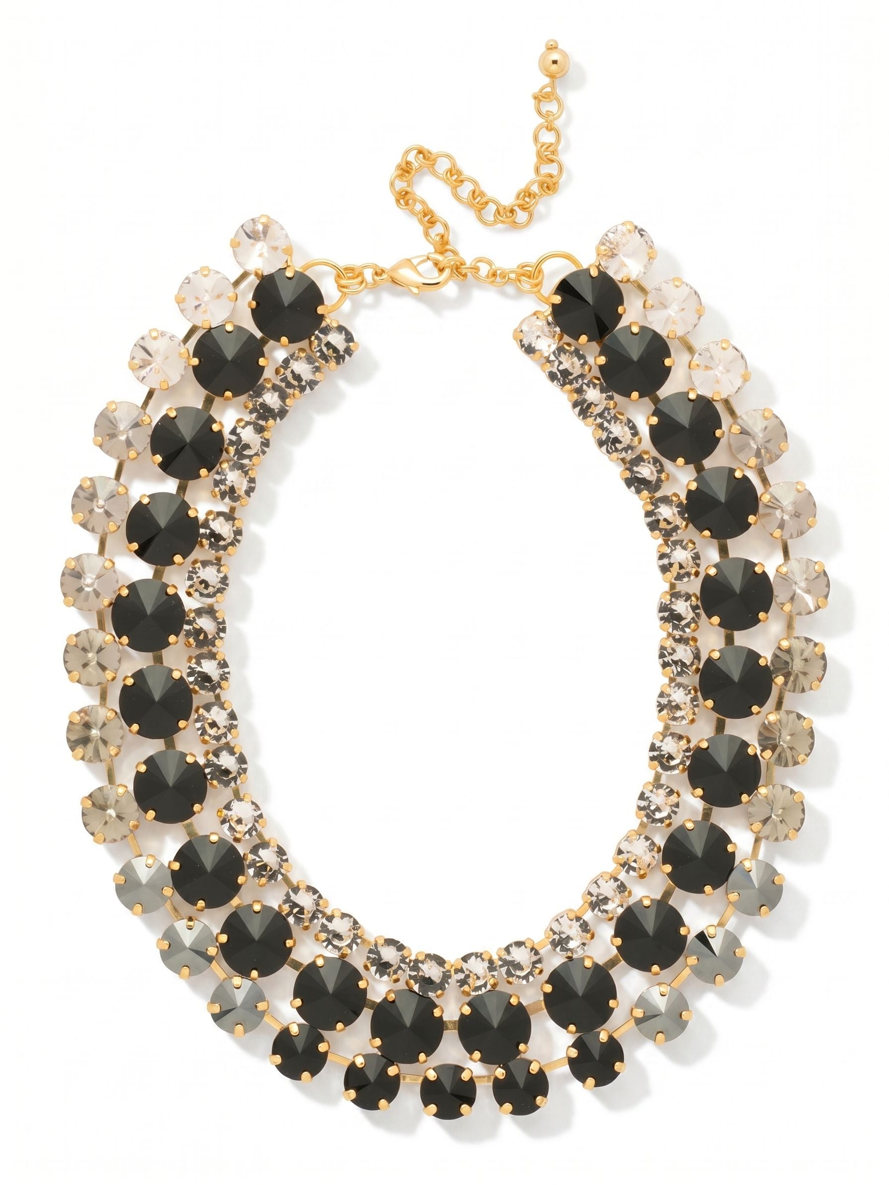 Penelope Layered Statement Necklace - NGB4BGSNI - <p>This three-row collar brings immediate architecture to your neckline. An inner channel of clear crystal rests close to the collarbone, anchoring a bold center row of oversized jet black stones. Along the outer edge, a carefully arranged gradient shifts from transparent crystal down through smoky black diamond and deep hematite. Built with a substantial weight that drapes securely, the structured tiers move as a single, cohesive piece. An extension chain lets you adjust the drop, ensuring this powerful design sits exactly where you want it.</p><ul>
<li>Three distinct rows create a structured collar silhouette</li>
<li>Outer crystal line shifts in a gradient from clear to dark hematite</li>
<li>Lobster claw clasp</li>
<li>4-inch adjustable extension chain</li>
<li>Protective e-coat finish for lasting wear</li>
<li>Includes signature organza pouch for gifting and travel</li>
</ul>