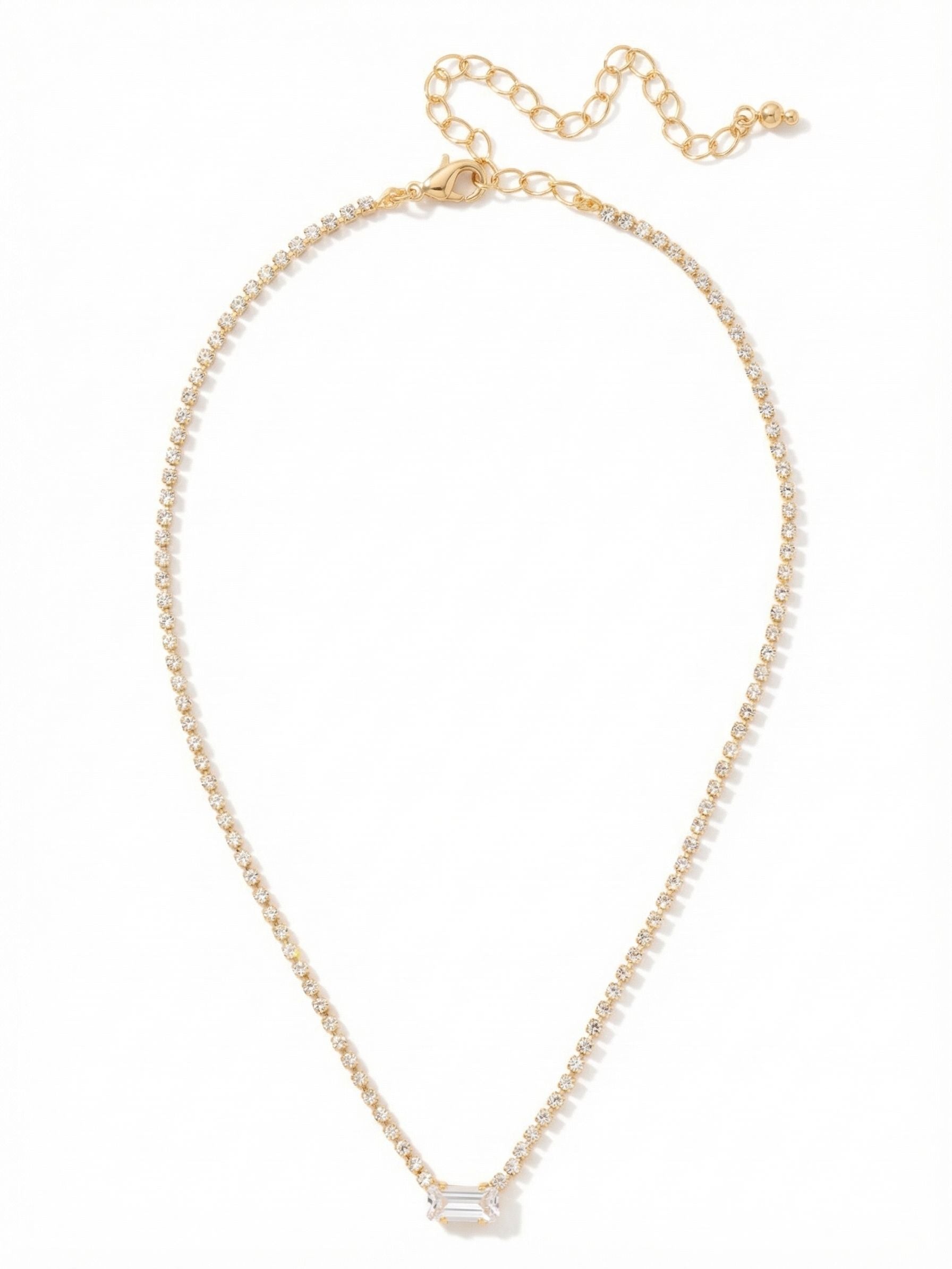 Mini Marnie Baguette Pendant Necklace - NGJ1BGCRY - <p>A slender line of tiny crystals traces the collarbone, anchoring a single rectangular step-cut stone at the center. The geometric cut of the focal crystal offers a clean flash of light that contrasts with the continuous shimmer of the delicate chain. Designed to sit high on the neckline, the built-in extension lets you adjust the drop to complement different collar shapes. It brings a quiet architecture to your daily layering rotation, providing just enough structure to stand apart.</p><ul>
<li>Horizontal rectangular step-cut focal crystal</li>
<li>Slender rhinestone chain for continuous light</li>
<li>Lobster claw clasp</li>
<li>4-inch adjustable extension chain</li>
<li>Protective e-coat finish for lasting wear</li>
<li>Includes signature organza pouch for gifting and travel</li>
</ul>