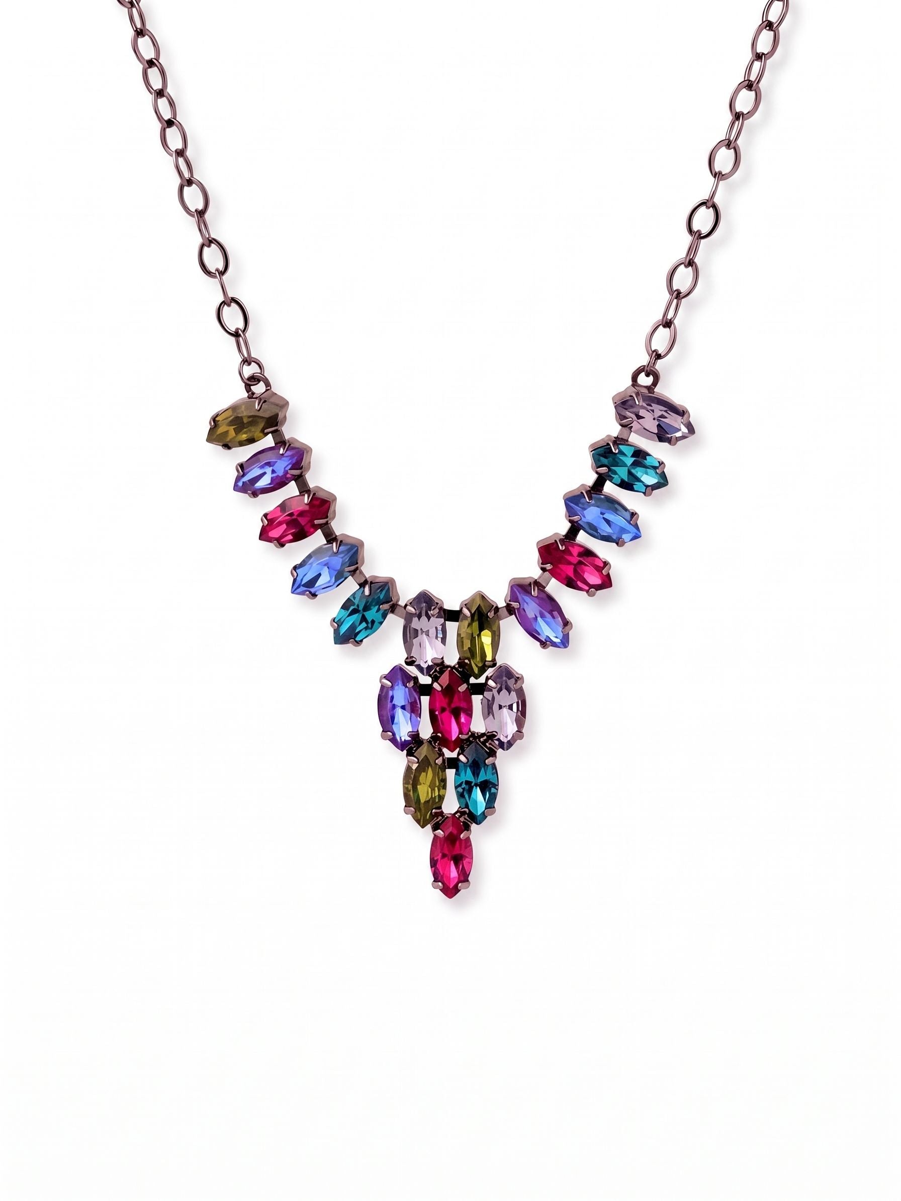 Clari Statement Necklace - NGK5GMNNI - <p>Eighteen marquise-cut crystals form a structured V-silhouette that frames the collarbone with architectural precision. Deep jewel tones of fuchsia, emerald, and tanzanite cluster into a pointed drop, set against a dark gunmetal backdrop that makes the saturated colors pop. A flexible cable chain anchors the arrangement, keeping the focus entirely on the complex geometry of the stones. The adjustable extension lets you tailor the drop length, allowing the focal point to hit perfectly whether worn over a high neckline or against bare skin.</p><ul>
<li>Structured V-neck drop formed by clustered marquise stones</li>
<li>Rich jewel-tone palette anchored by a dark metal setting</li>
<li>Lobster claw clasp</li>
<li>4-inch adjustable extension chain</li>
<li>Includes signature organza pouch for gifting and travel</li>
</ul>