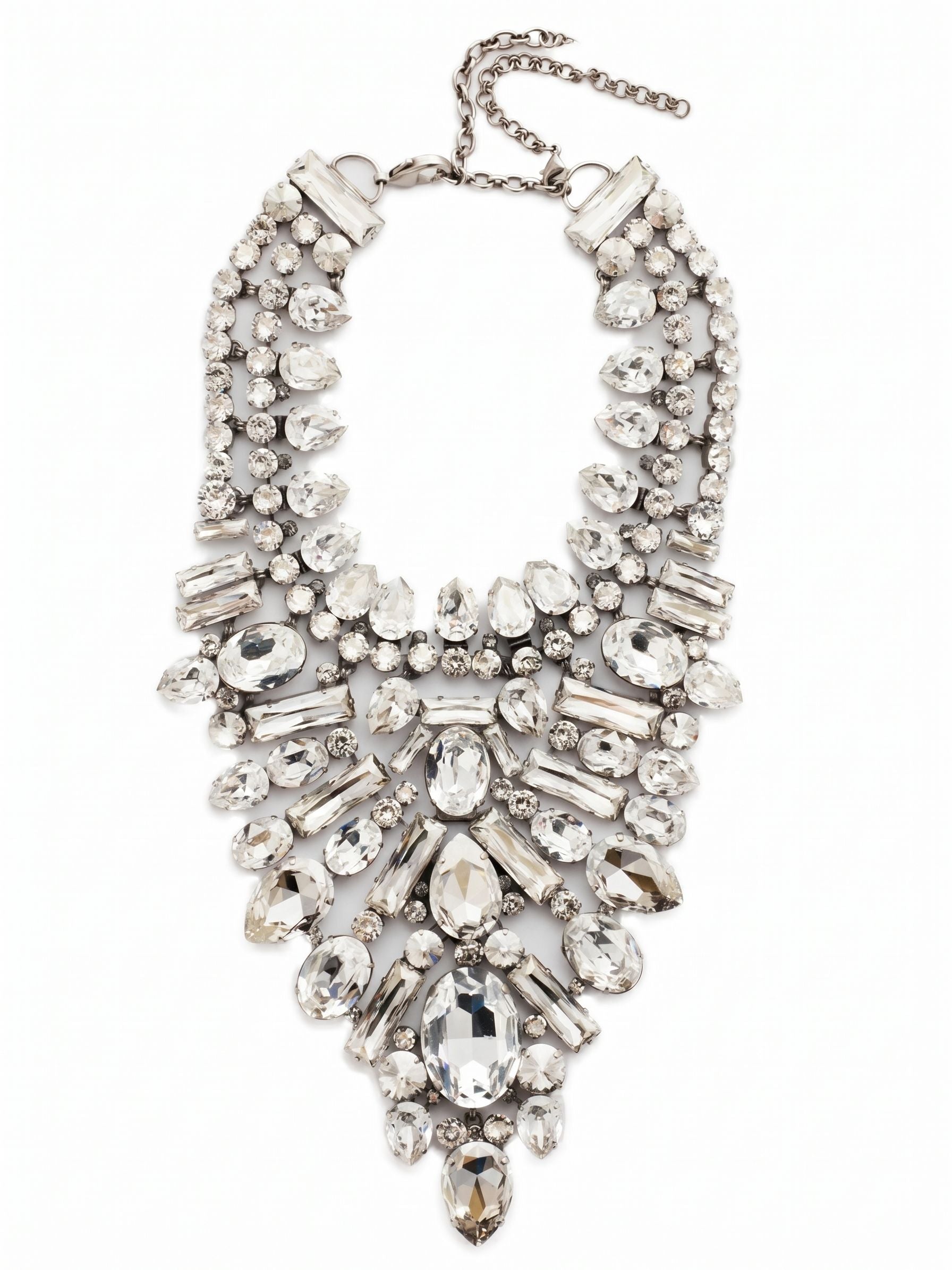 Crystal Cluster Statement Necklace - NSP80ASSSH - <p>This intricate bib necklace rests with deliberate weight across the collarbones, anchoring a deep plunge of meticulously arranged crystals. Seventeen distinct variations of pear, baguette, and oval stones create a textured, architectural piece that catches light from every angle. The foundation of ladder and channel chains allows the substantial design to articulate gently with your movements, preventing it from feeling rigid. Finished with an extension chain to dial in the drape perfectly, this piece commands the room with a quiet, icy confidence.</p><ul>
<li>Architectural mix of oval, pear, and baguette crystals creates a brilliant sunburst effect</li>
<li>Articulating ladder and channel chains allow the dense bib to move comfortably</li>
<li>Lobster claw clasp</li>
<li>Includes signature organza pouch for gifting and travel</li>
</ul>