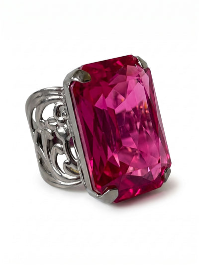 Viretta Adjustable Cocktail Ring - RBT67GMFU - <p>A singular, oversized emerald-cut crystal anchors this substantial cocktail ring. The deep fuchsia stone holds significant weight and presence, catching the light as your hands move through the day. We set this vivid focal point atop an intricately detailed band cast in dark metal, providing a grounded contrast to the bright gem. The open band allows you to comfortably shape the ring to whichever finger feels right.</p><ul>
<li>Single large emerald cut offers a bold geometric profile</li>
<li>Intricate scrollwork along the band contrasts the sharp crystal facets</li>
<li>Adjustable ring band</li>
<li>Includes organza pouch for gifting and travel</li>
</ul>