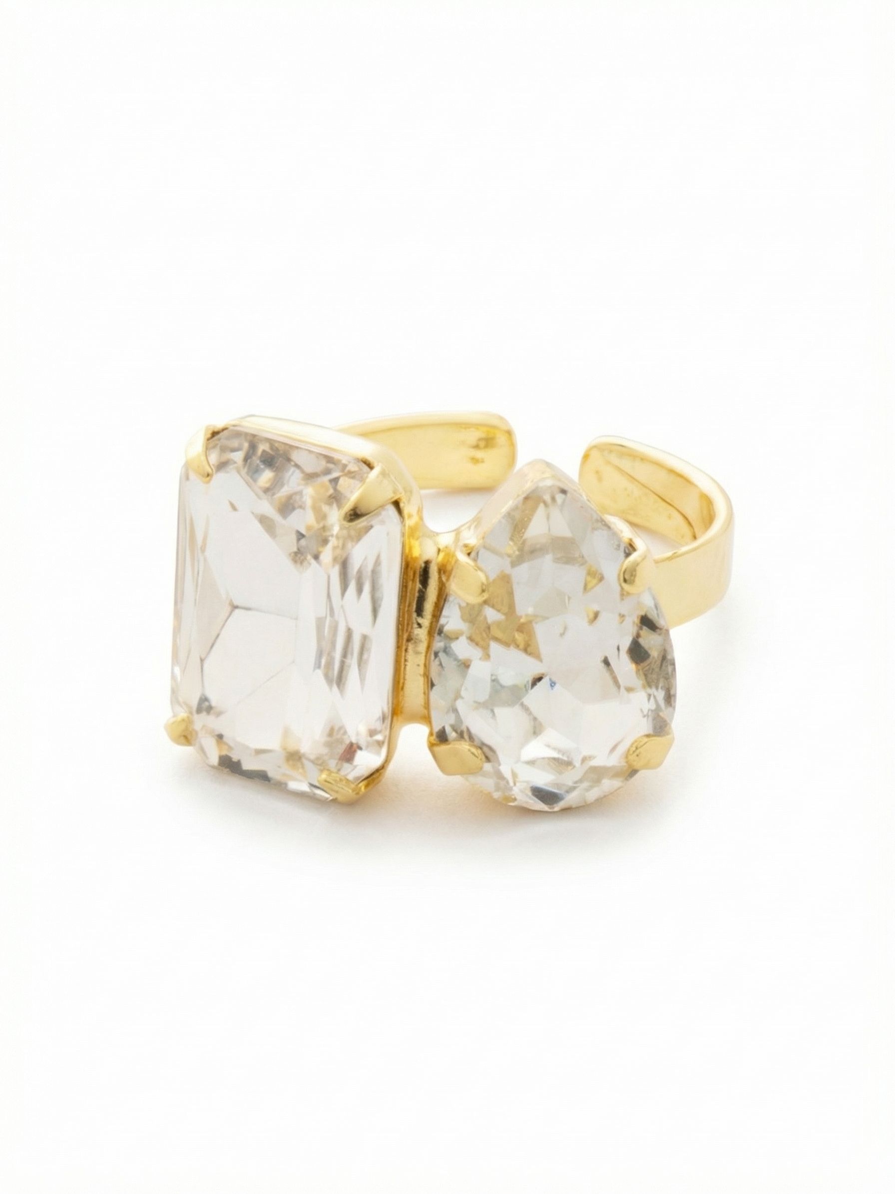 Emerald Pear Cocktail Ring - RFN3BGCRY - <p>Two distinct crystal shapes find balance on the hand. An architectural emerald cut rests beside a softer pear shape, creating an intentional contrast that catches light differently with every gesture. The bright metal setting frames the clear stones cleanly, drawing the eye without overwhelming your daily rotation. Designed for real life, the open band construction offers a forgiving fit and gives you the freedom to easily shift the ring between fingers depending on your mood.</p><ul>
<li>Asymmetric side-by-side design pairing emerald and pear shapes</li>
<li>Generous scale that reads clearly across a room</li>
<li>Adjustable ring band</li>
<li>Protective e-coat finish for lasting wear</li>
<li>Includes signature organza pouch for gifting and travel</li>
</ul>