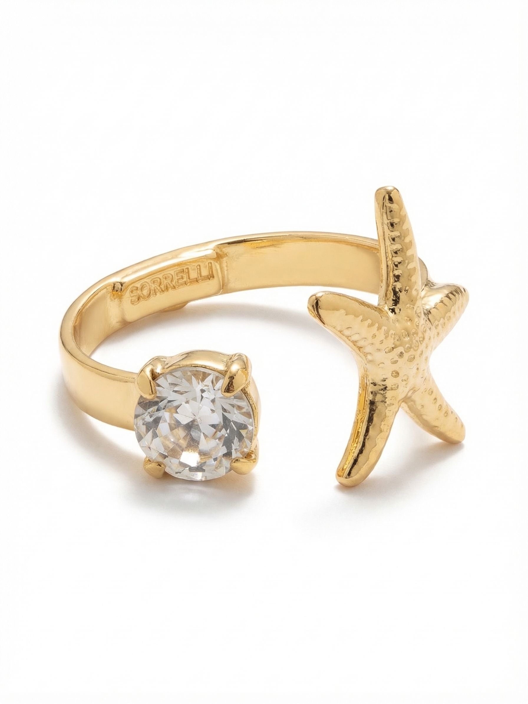 Starfish Open Band Ring - RGE3BGCRY - <p>A delicate study in balance. This open ring pairs a textured gold-tone starfish with a single round clear crystal, creating a subtle tension as the two elements meet across your finger. The adjustable band gives you the flexibility to switch it from ring finger to index finger depending on your mood. It brings a refined coastal energy to your daily rotation, catching the light easily as you talk with your hands.</p><ul>
<li>Open-band silhouette creates negative space between the crystal and textured starfish</li>
<li>Gently adjustable shape allows for effortless finger styling</li>
<li>Adjustable ring band</li>
<li>Protective e-coat finish for lasting wear</li>
<li>Includes signature organza pouch for gifting and travel</li>
</ul>