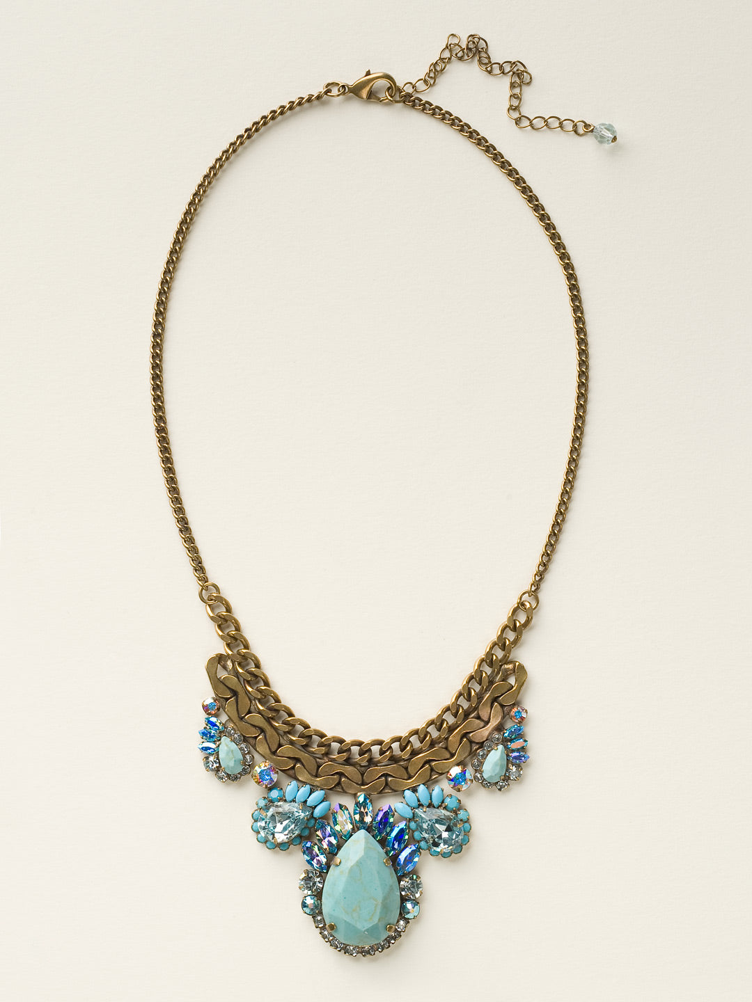 Graduated Pear Statement Necklace - NCU17AGAZ - Metal and sparkle have never looked so good! Five variously sized teardrop stones accented with feathered marquis crystals hang from a thick curb chain. From Sorrelli's Azure Allure collection in our Antique Gold-tone finish.